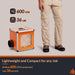 Compact orange HEPA 600 UVIG air scrubber beside a technician's legs, highlighting 600 CFM airflow and lightweight 36 lb portable design