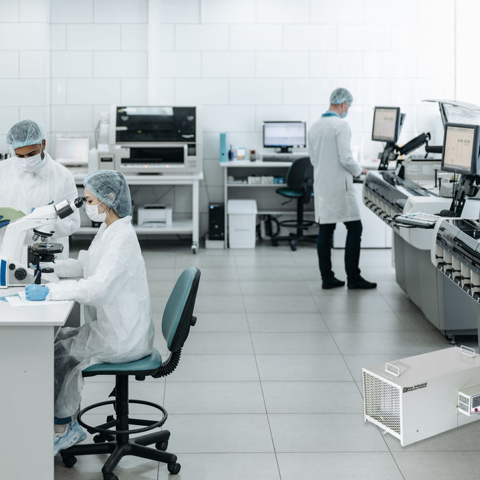 EBac CD30-SE Industrial Portable Dehumidifier, featuring a capacity of 170 cubic feet per minute, situated in a laboratory setting with two technicians, one examining a sample under a microscope and another operating analytical equipment in the background.