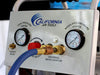 Close-up of California Air Tools air compressor front panel with pressure gauges, regulator knob, universal quick coupler, and air hose attached.