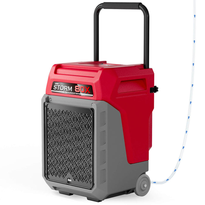 AlorAir Storm 80X commercial dehumidifier in red, shown at an angle with drain hose attached