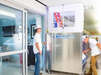 Two people installing the HEPACART  AutoLift Mobile Containment in a  hospital hall. 